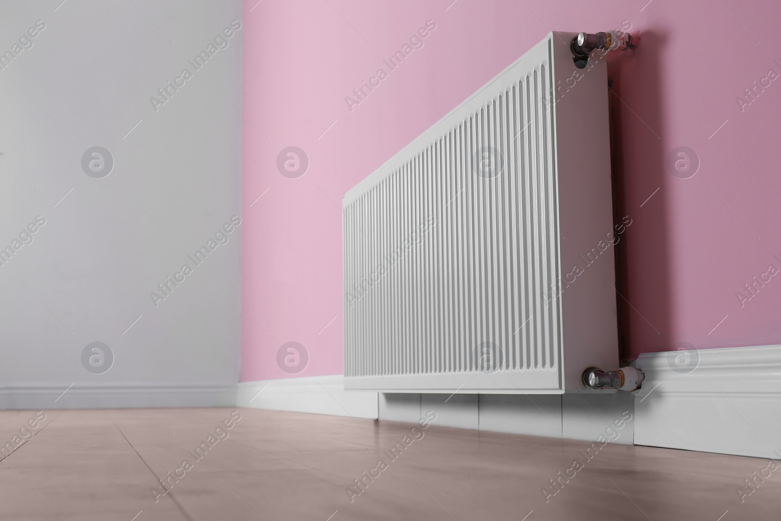 Photo of Modern radiator on color wall indoors. Central heating system