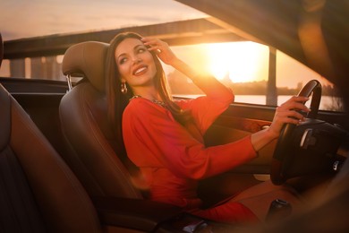 Photo of Sexy woman driving luxury convertible car at sunset