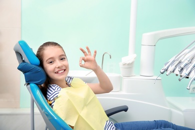 Photo of Happy little girl having dentist's appointment in modern clinic