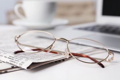 Photo of Newspapers and glasses on white table, closeup