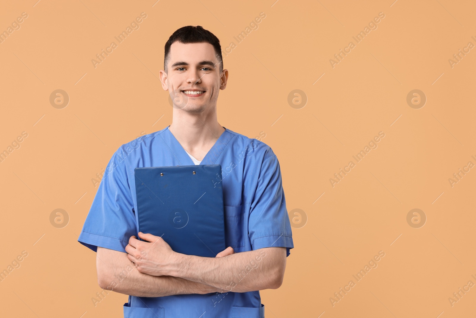 Photo of Portrait of smiling medical assistant with clipboard on beige background. Space for text