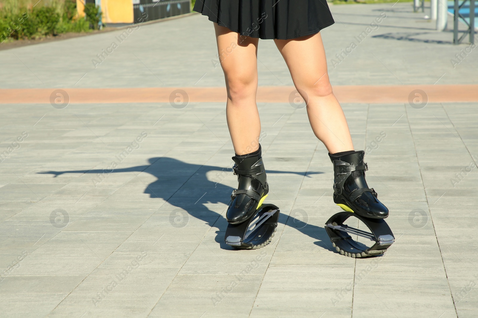 Photo of Woman in kangoo jumping boots outdoors on sunny day, closeup