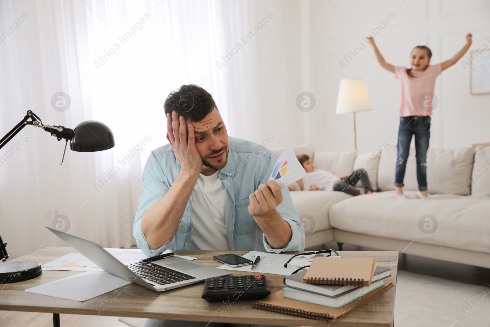 Photo of Overwhelmed man combining parenting and work at home