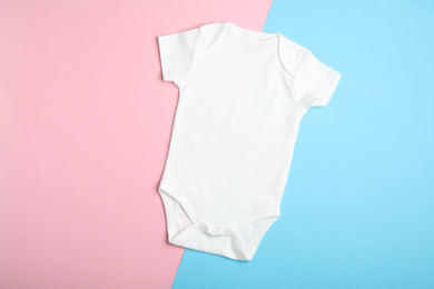 Child's bodysuit on light blue and pink background, top view