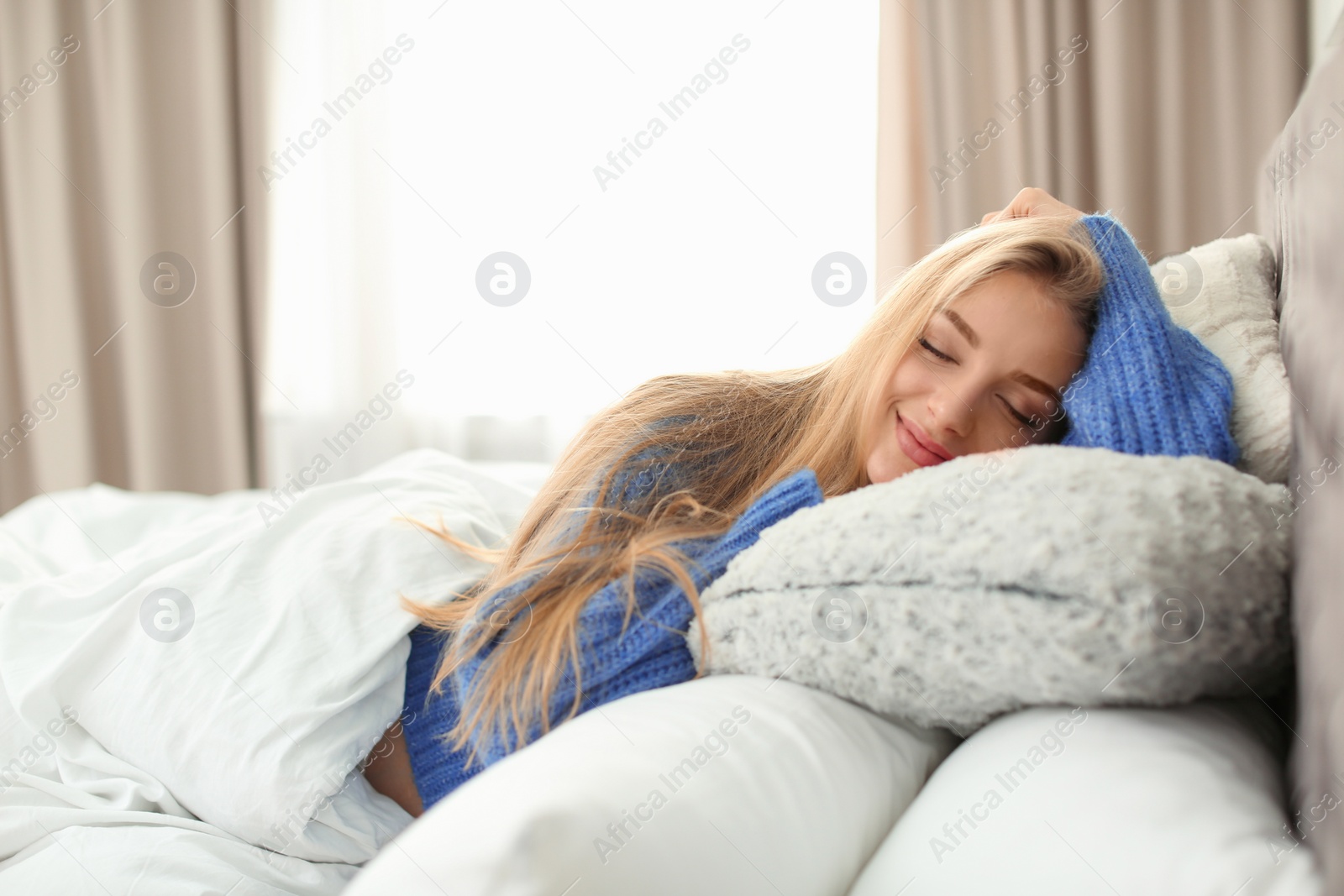 Photo of Beautiful young woman sleeping in bed with many pillows at home. Winter atmosphere