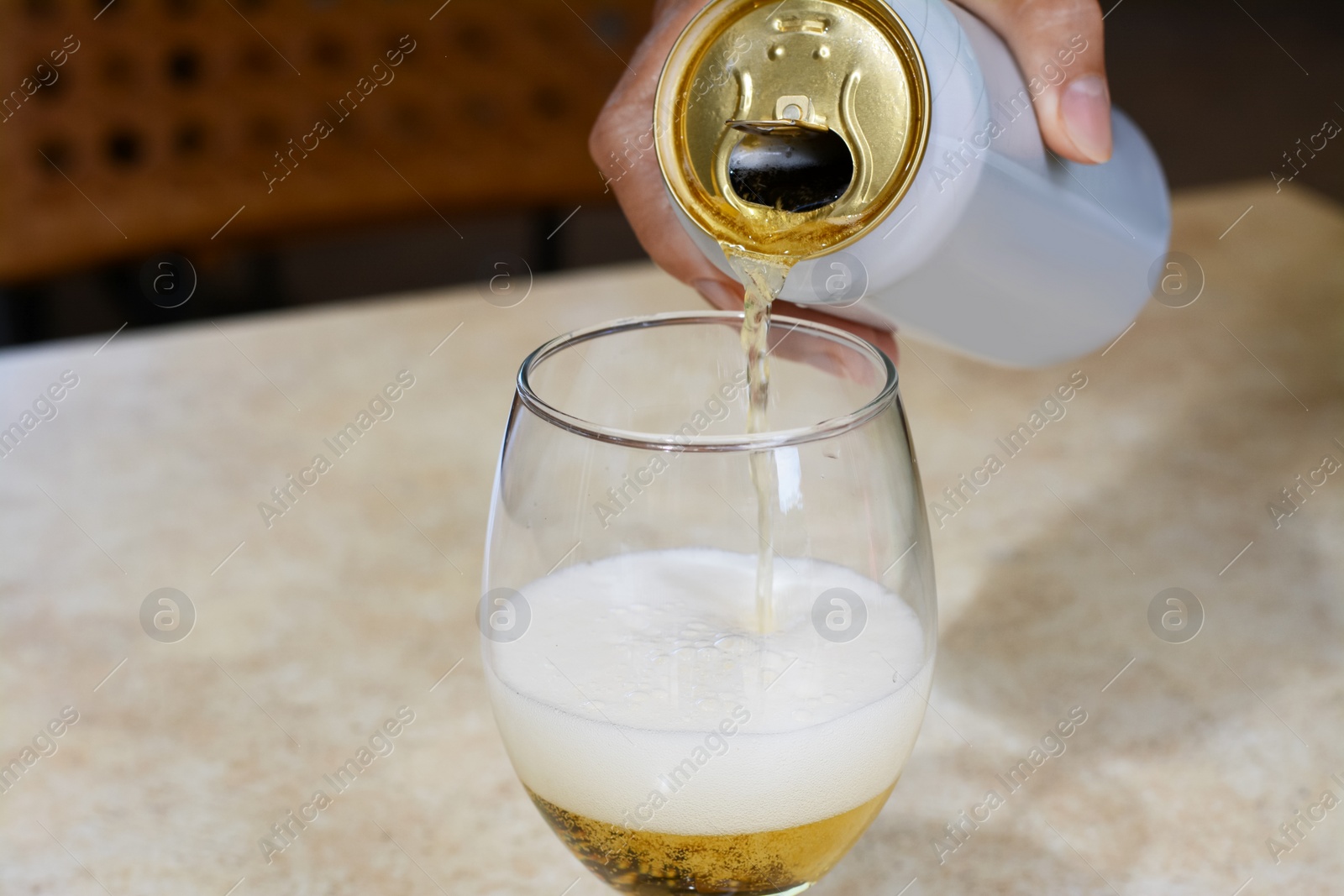 Photo of Man pouring beer from can into glass at table, closeup