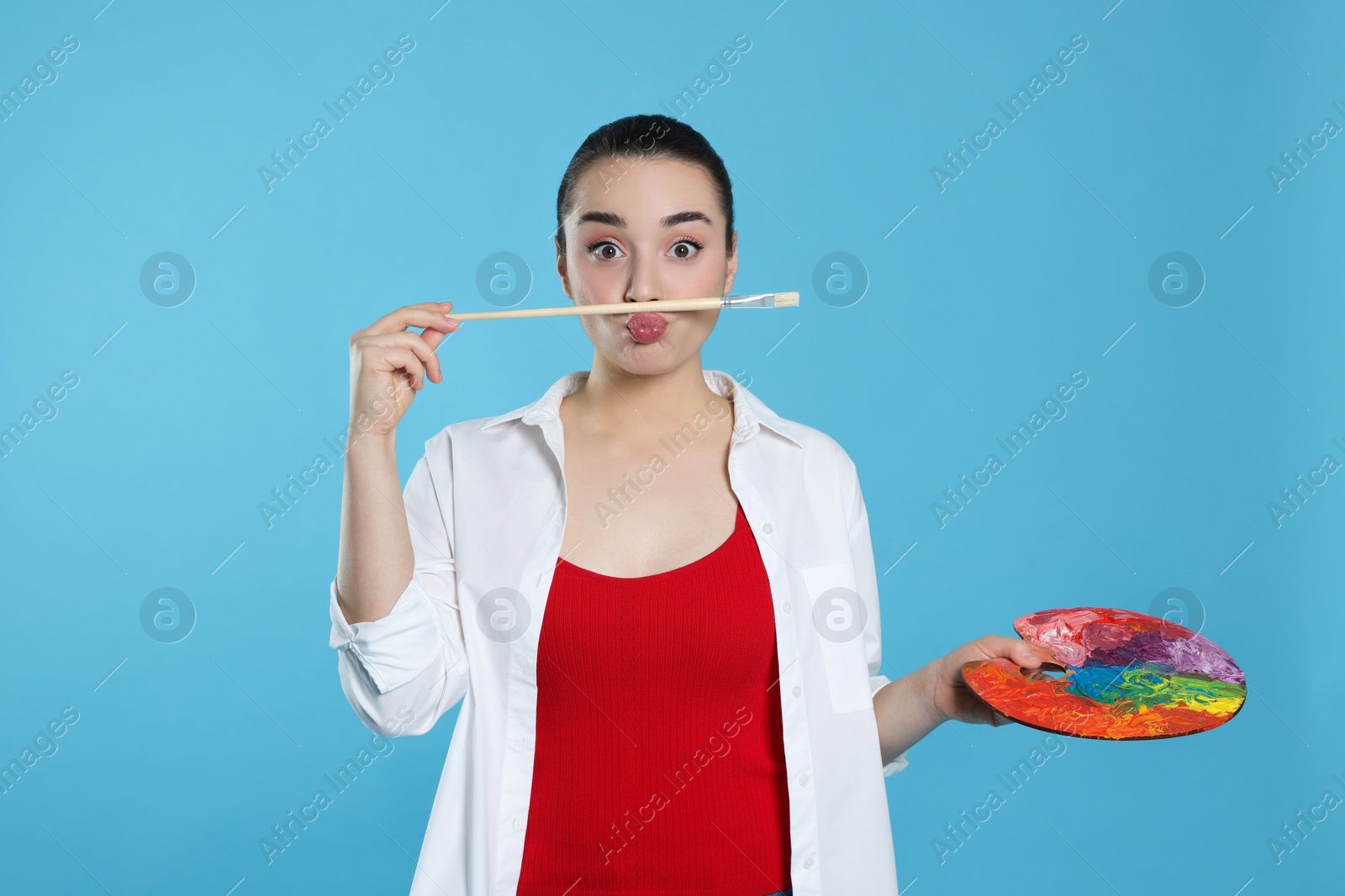 Photo of Woman with painting tools on light blue background. Young artist