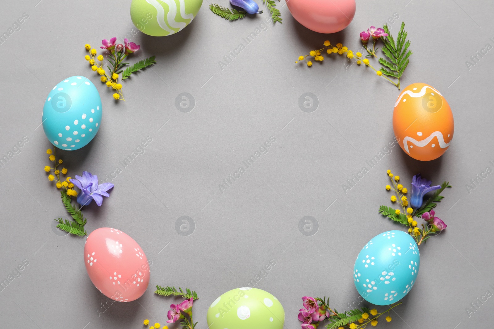 Photo of Flat lay composition of painted Easter eggs and flowers on color background, space for text