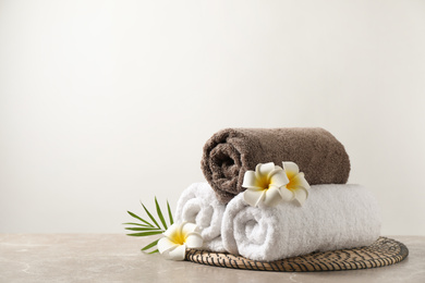 Photo of Beautiful spa composition with plumeria flowers on grey marble table against light background. Space for text
