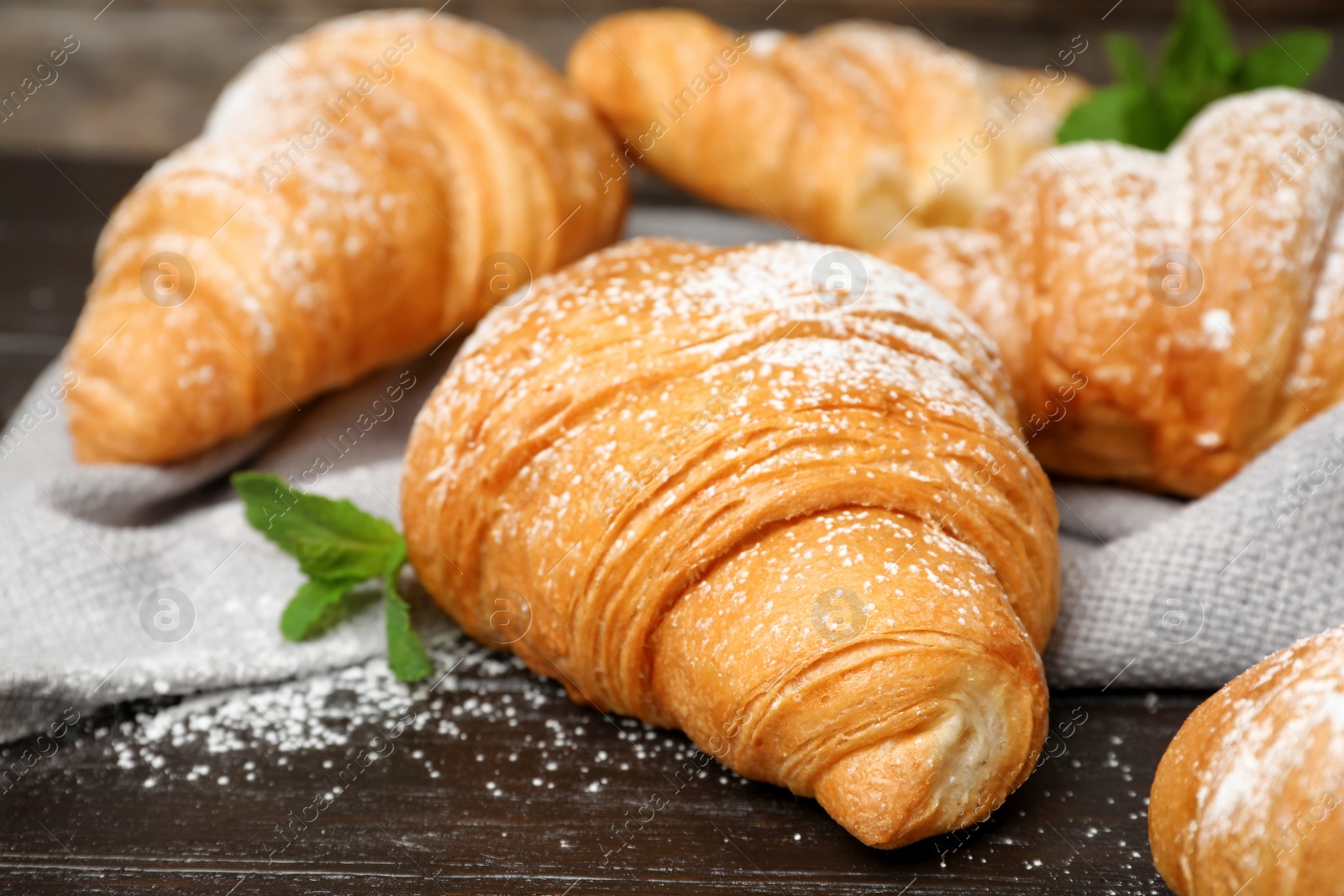 Photo of Tasty croissants with sugar powder on table, closeup