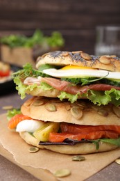 Photo of Stacked tasty bagel sandwiches on brown table, closeup