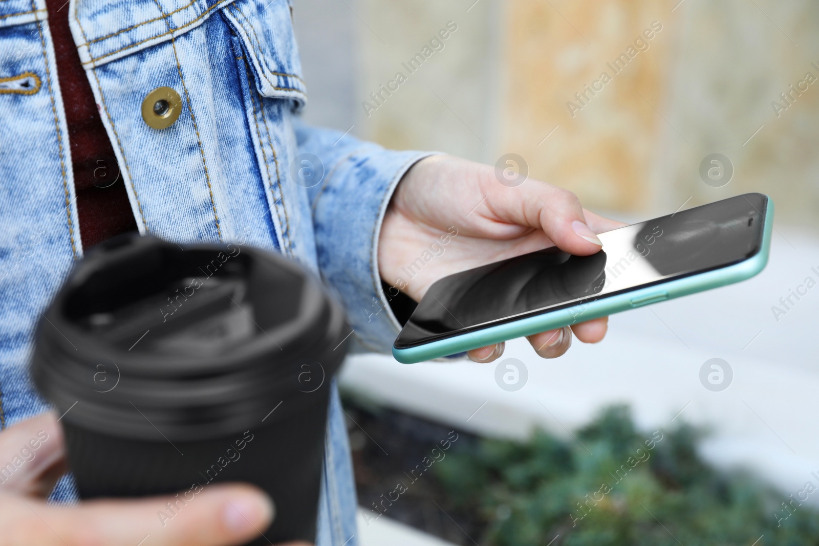 Photo of Woman with coffee using smartphone outdoors, closeup