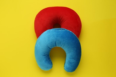 Photo of Colorful travel pillows on yellow background, top view