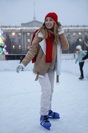 Happy young woman skating at outdoor ice rink