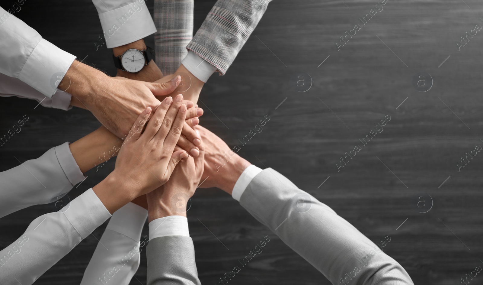 People holding hands together over grey wooden background, top view. Unity concept Photo of People holding hands together over grey wooden background, top view. Unity concept