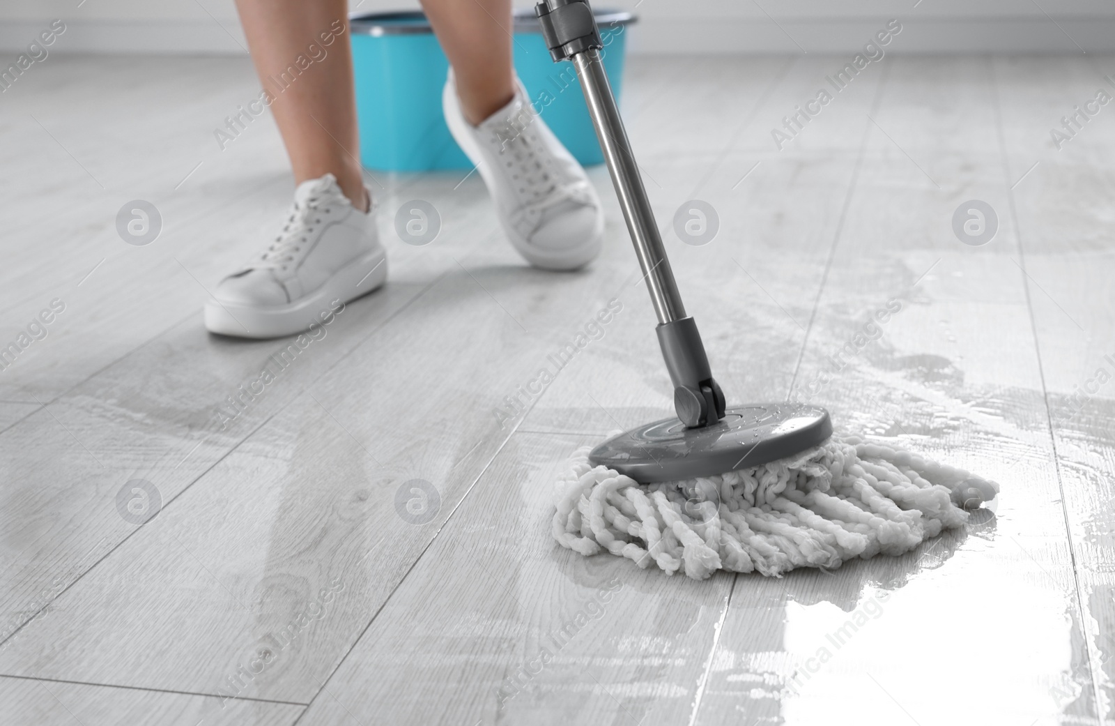 Photo of Woman cleaning floor with mop indoors, closeup