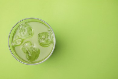 Photo of Glass of delicious iced matcha tea on green background, top view. Space for text