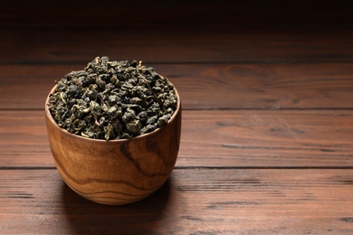 Photo of Bowl of Tie Guan Yin oolong tea leaves on wooden table. Space for text