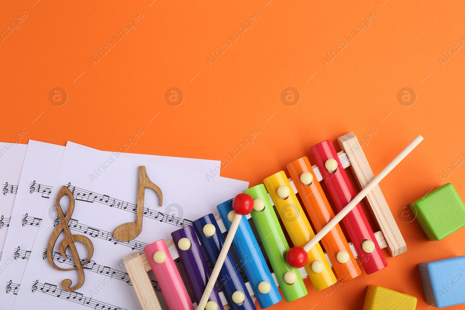 Photo of Tools for creating baby songs. Flat lay composition with xylophone on orange background. Space for text