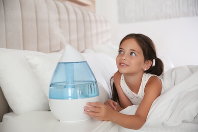 Cute little girl in bedroom with modern air humidifier