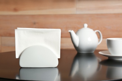 Photo of Ceramic napkin holder with paper tissues on served table. Tea time