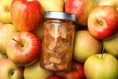 Delicious apple jam in jar on fresh fruits, top view