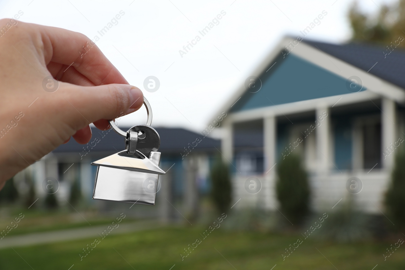 Photo of Woman holding house keys outdoors, closeup with space for text. Real estate agent