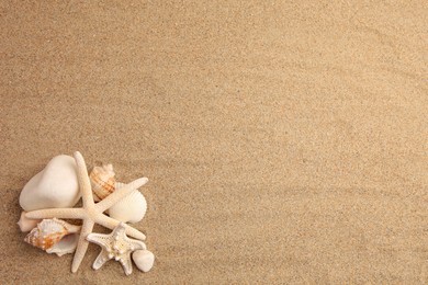 Beautiful sea stars, shells and stones on sand, flat lay. Space for text