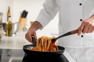 Photo of Professional chef cooking delicious pasta on stove in kitchen, closeup