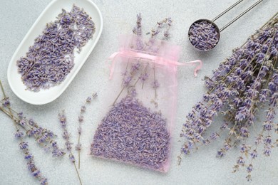 Photo of Scented sachet and dried lavender flowers on light gray textured table, flat lay