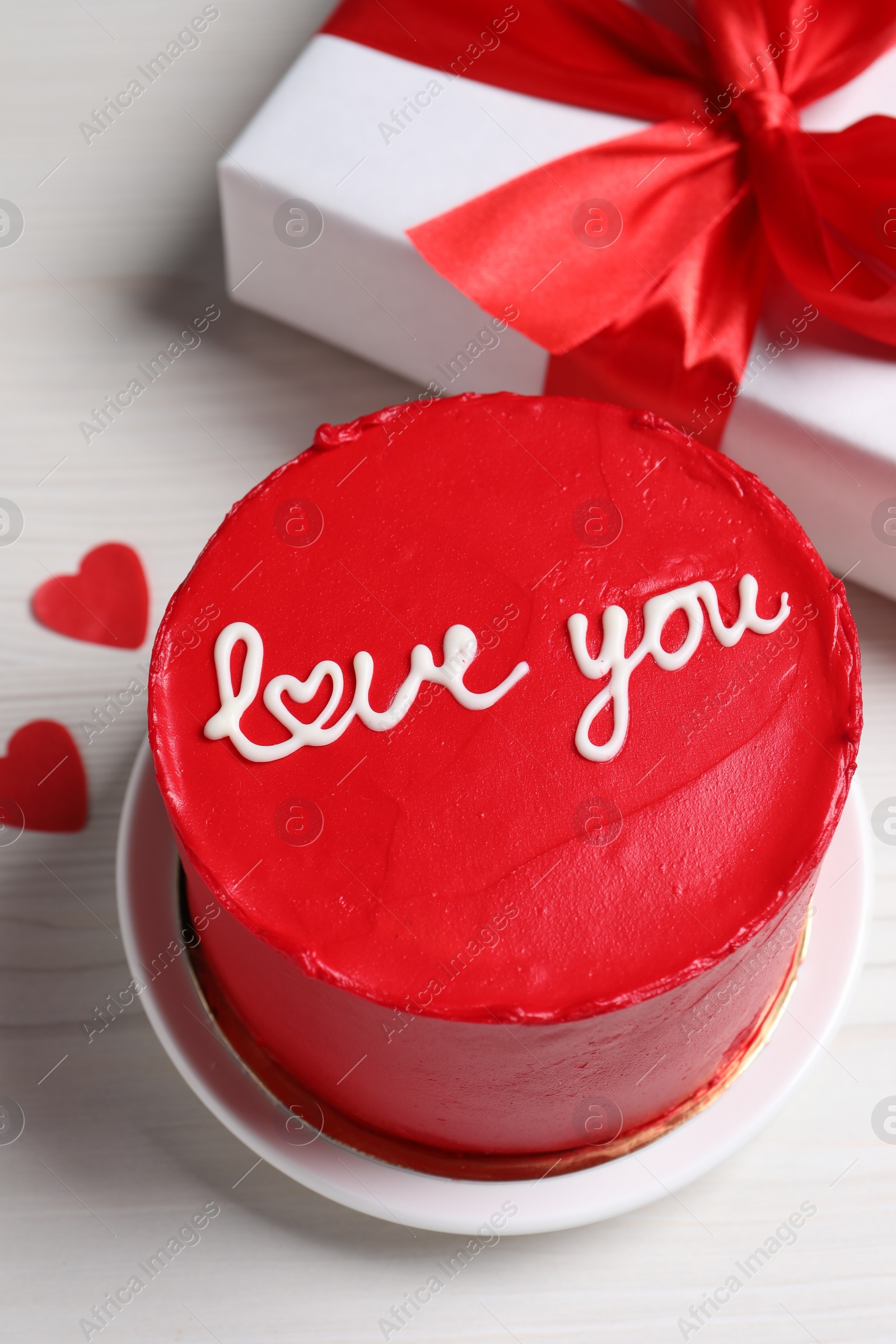 Photo of Bento cake with text Love You, gift box and paper hearts on white wooden table. St. Valentine's day surprise