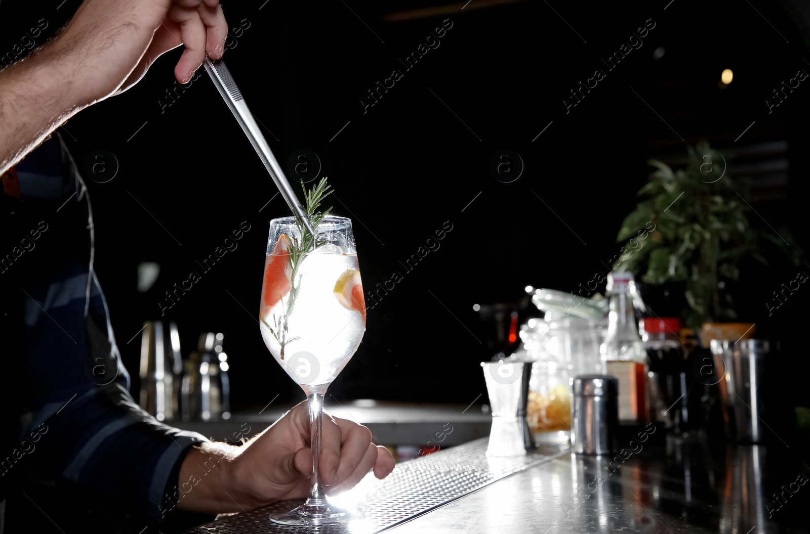 Photo of Barman making grapefruit gin tonic cocktail at counter in pub, closeup. Space for text