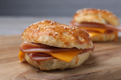 Photo of Delicious bagels with ham and cheese on wooden table, closeup