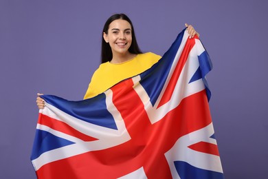 Photo of Happy young woman with flag of United Kingdom on violet background
