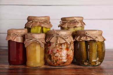 Photo of Many jars with different preserved ingredients on wooden table