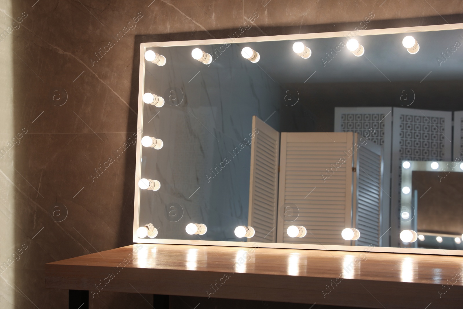 Photo of Modern mirror with light bulbs on wooden table in room