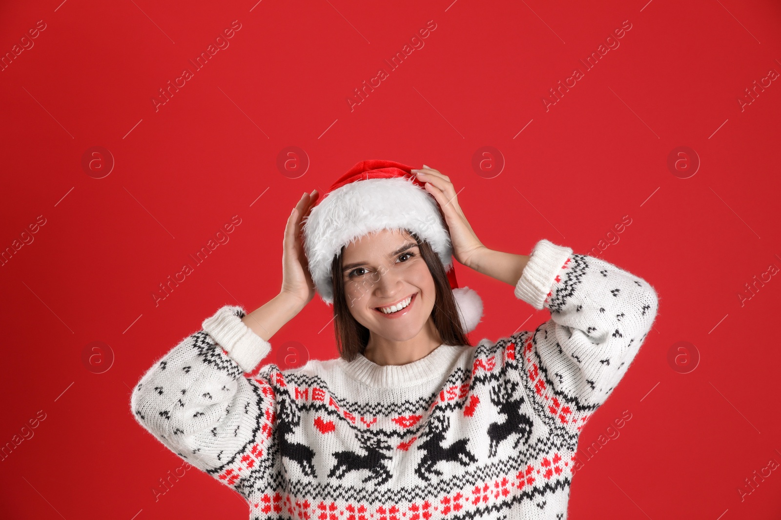 Photo of Pretty woman in Santa hat and Christmas sweater on red background