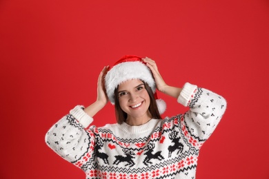 Pretty woman in Santa hat and Christmas sweater on red background