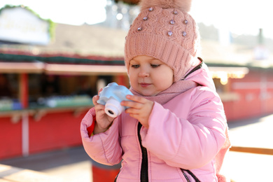 Photo of Cute little photographer with toy camera outdoors