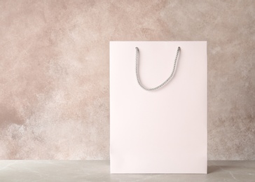 Photo of Mockup of paper shopping bag on table against color background