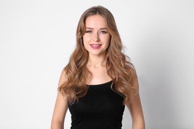 Portrait of young woman with long beautiful hair on light background