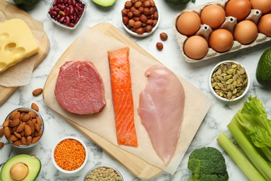 Photo of Different fresh products on white marble table, flat lay. Sources of essential amino acids