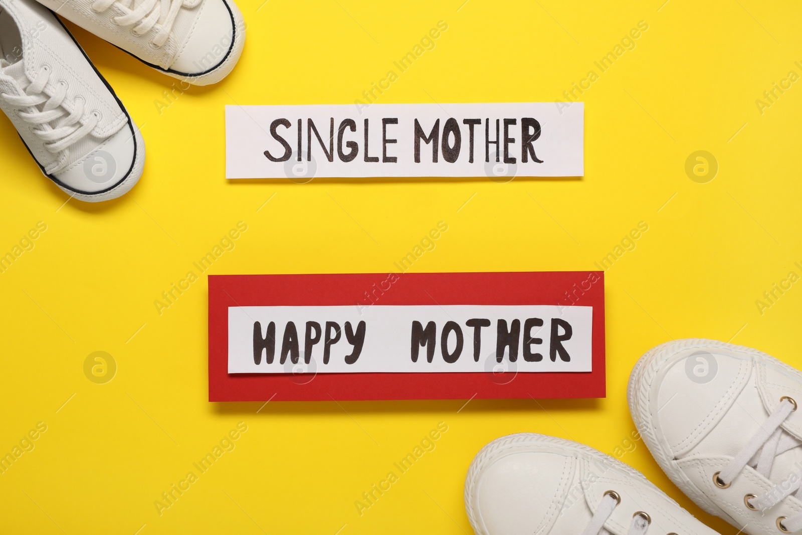 Photo of Being single mother concept. Children's and woman's gumshoes on yellow background, flat lay