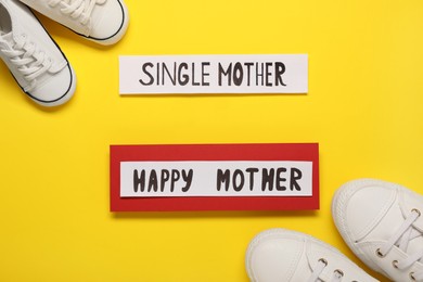 Photo of Being single mother concept. Children's and woman's gumshoes on yellow background, flat lay
