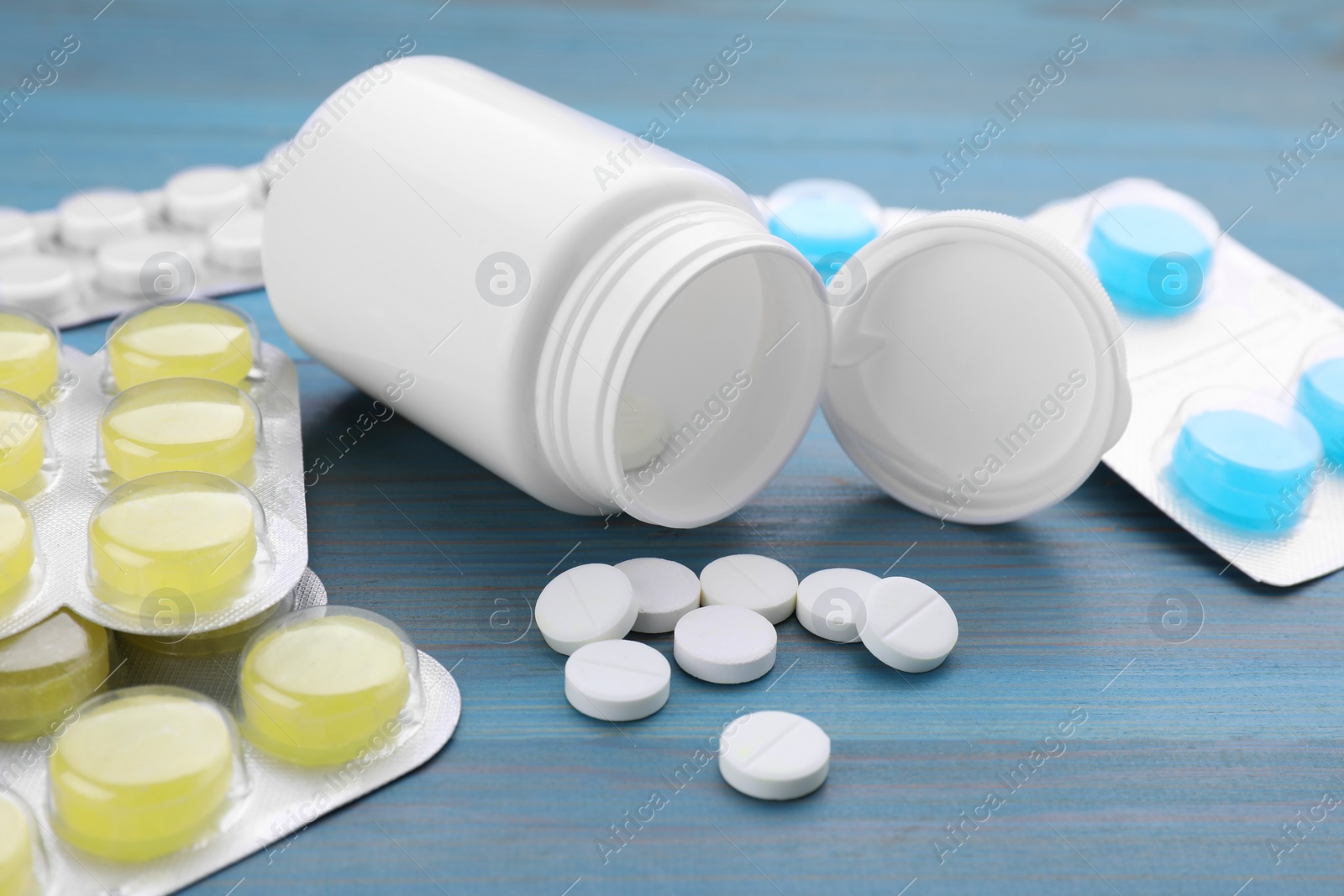 Photo of Cold remedies. Many different pills on light blue wooden table, closeup. Cough treatment