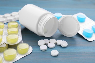 Photo of Cold remedies. Many different pills on light blue wooden table, closeup. Cough treatment