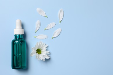 Photo of Bottle of cosmetic serum, beautiful flower and petals on light blue background, flat lay. Space for text