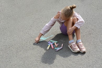 Little child drawing flower with chalk on asphalt, space for text