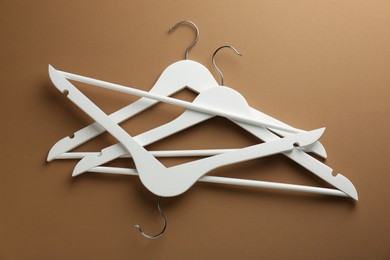 White hangers on brown background, top view