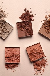 Photo of Different crushed eye shadows on beige background, flat lay